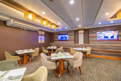 a restaurant with tables and chairs and a flat screen tv at Holiday Inn - Bulawayo by IHG in Bulawayo