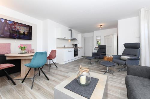 a living room with a couch and chairs and a kitchen at Ferienwohnung Seepferdchen in Bensersiel