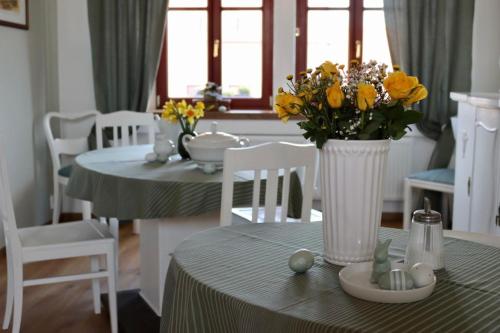 a dining room with a table with yellow flowers in a vase at Penzion U Kapra in Roudnice nad Labem