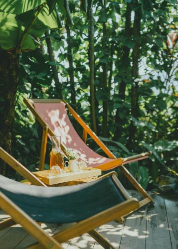 a chair sitting on a deck with a drink in it at The Wooden Gate in Xuân Sơn