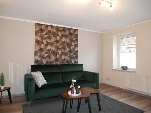a living room with a green couch and a table at Ferienwohnung Mecklenburgische Seenplatte in Schwichtenberg
