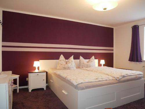 a bedroom with a white bed with a purple wall at Ferienwohnung Mecklenburgische Seenplatte in Schwichtenberg