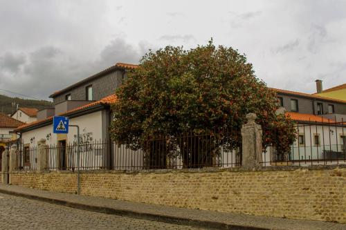 a fence with a tree in front of a building at Casa de Campo Vale do Ceira in Góis