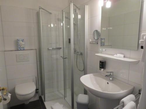 uma casa de banho com um chuveiro, um lavatório e um WC. em Hotel zum Rosenteich em Bad Zwischenahn