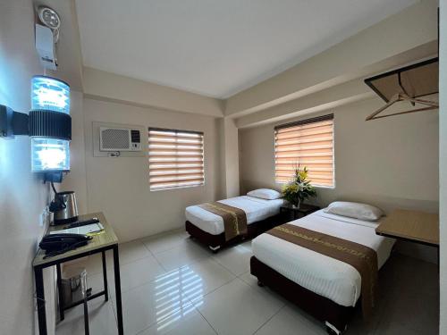 ein Hotelzimmer mit zwei Betten und zwei Fenstern in der Unterkunft Eon Centennial Express Hotel in Iloilo City