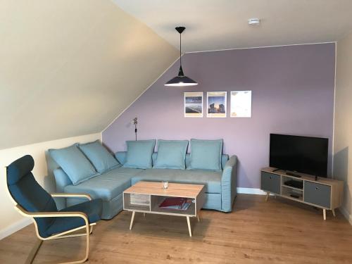 a living room with a blue couch and a tv at Ferienwohnungen Koch OG adult only in Wangerland