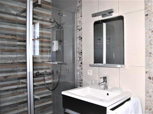 W łazience znajduje się umywalka i prysznic. w obiekcie Hotel Le Goeland w mieście Barbâtre