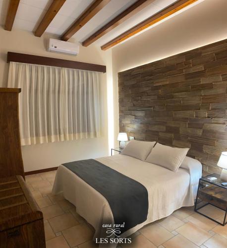 a bedroom with a bed and a brick wall at Casa rural Les Sorts in Rosell