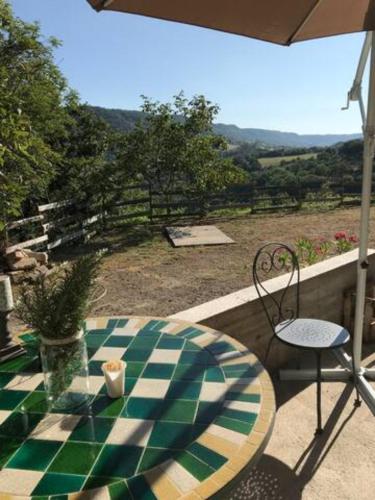 a table and chair on a patio with a view of a field at Petite Maison pleine nature in La Bastide-Pradines