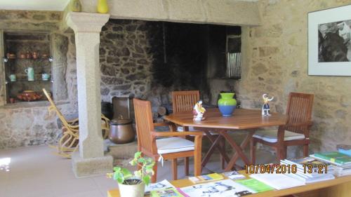 a dining room with a table and chairs and a stone wall at Casa rural A Mimoseira in A Estrada