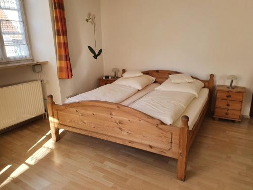 a bedroom with a wooden bed with white sheets at Hotel Andreasstuben in Weißenburg in Bayern