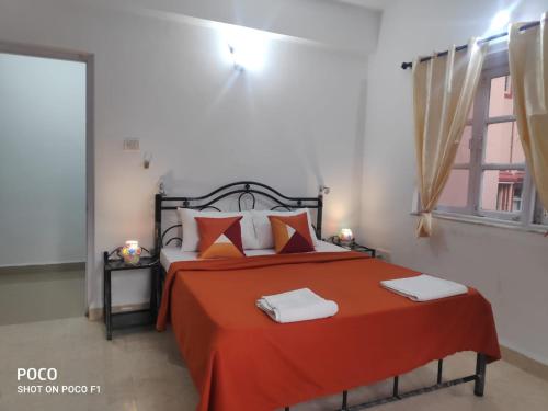 Un dormitorio con una cama con sábanas rojas y una ventana en 2 bhk Calangute - Baga road Saldanha Kyle Gardens, en Calangute