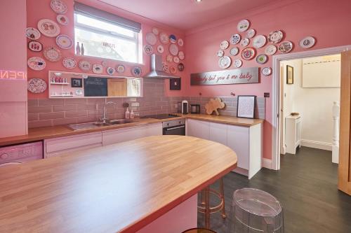 une cuisine avec des murs roses et un comptoir en bois dans l'établissement Host & Stay - The Artists Pad, à Saltburn-by-the-Sea