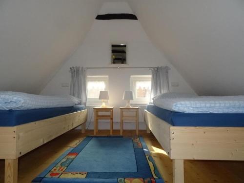 2 Betten in einem Zimmer mit 2 Fenstern und einem Teppich in der Unterkunft Ferienhaus 257 R in Eckwarden in Eckwarden