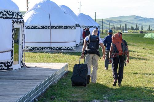 a group of people with backpacks and luggage walking towards tents at Karkyra Yurt Glamping in Sarytëbë