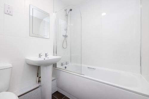 La salle de bains blanche est pourvue d'un lavabo et d'une douche. dans l'établissement JOIVY Bright 3-bed flat overlooking The Clyde, à Glasgow