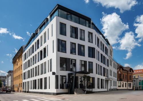 a white building with black windows on a street at Piano apartments - LICITY in Žilina