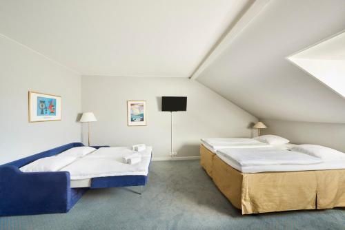 two beds in a attic room with a tv at Zleep Hotel Prindsen Roskilde in Roskilde