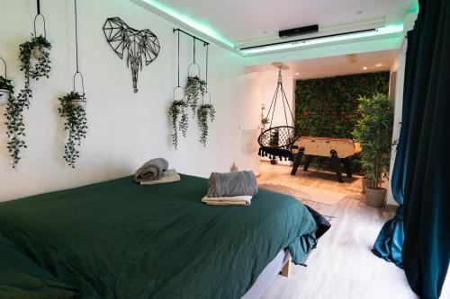 a bedroom with a green bed with plants on the wall at Capsule Thailande I Sauna I Balnéo I Console I jeux en bois I Cinéma I cour intérieure in Trith-Saint-Léger
