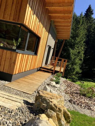 a house with a wooden deck next to a yard at Chalet Slovensky Raj in Smižany