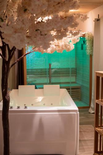 a bath tub with a tree in front of a window at Capsule Thailande I Sauna I Balnéo I Console I jeux en bois I Cinéma I cour intérieure in Trith-Saint-Léger