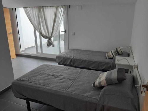 two beds in a room with a window at Roses Casc Antic SL Avgda de Rhode in Roses