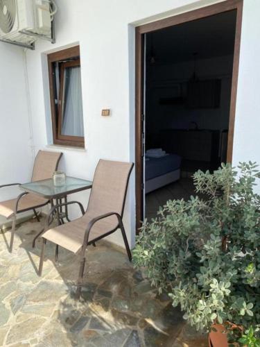 a patio with two chairs and a glass table and a table at Kasteli Studios & Apartments in Panormos Rethymno