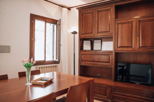a dining room with a wooden table and a television at Bricola Biennale Apartments in Venice
