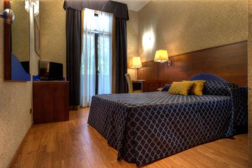 a bedroom with a bed with a blue comforter at Central Park Hotel Modena in Modena