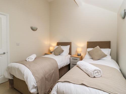 2 camas individuales en una habitación con 2 lámparas en The Coach House, en Keighley