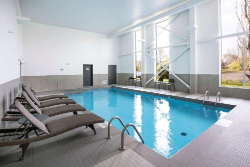 a large swimming pool with chairs and a large window at Quality Inn in Quebec City