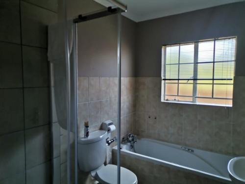 a bathroom with a toilet and a tub and a sink at Town House at The Reeds in Centurion