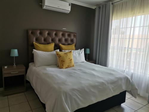 a bedroom with a large white bed with yellow pillows at Town House at The Reeds in Centurion