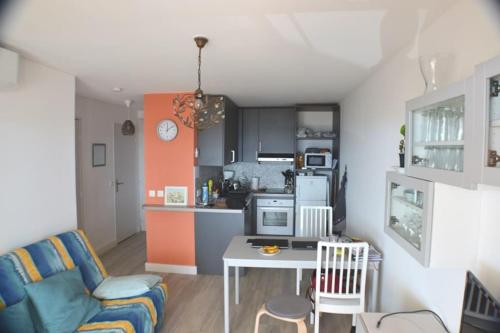 Il dispose d'une cuisine et d'un salon avec un canapé et une table. dans l'établissement 2 Piéces Clim Face a la plage vue Mer, à Cavalaire-sur-Mer