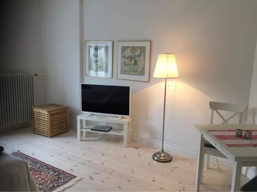 a living room with a television and a table with a lamp at Hotell Villa Rönne in Ängelholm
