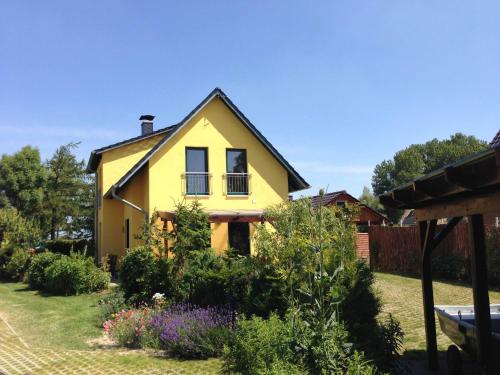a yellow house with two windows in a yard at Ferienhaus am Saaler Bodden in Neuendorf