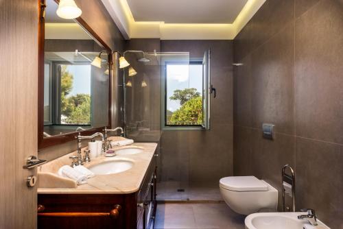 a bathroom with two sinks and a toilet and a window at Villa Benedetta Unique Privacy And Sea View in Sivota