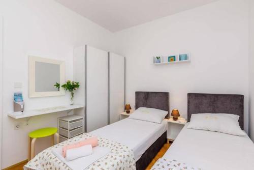 two beds in a small room with a green chair at Dubrovnik: Apartment Quiet Corner in Dubrovnik