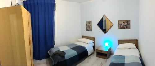 マルツァメミにあるLa Casa di Angelica Marzamemiのベッド2台と青いカーテンが備わる客室です。