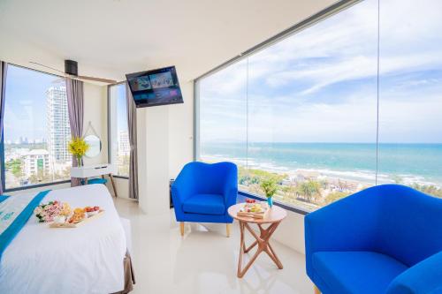 a bedroom with a bed and two chairs and a view of the ocean at Annata Beach Hotel in Vung Tau