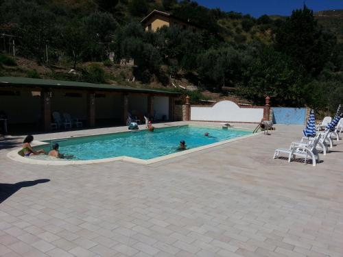 a swimming pool with people sitting in the water at L'Uliveto in Reitano