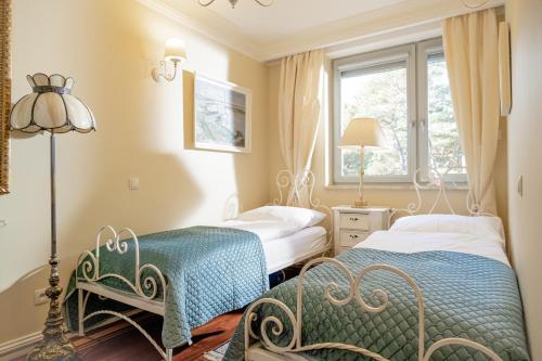 two beds in a bedroom with a lamp and a window at Dariusz Apartament PREMIUM Jurata z garażem in Jurata