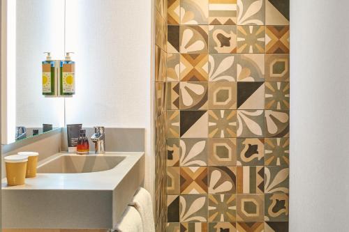 a bathroom with a sink and a tile wall at ibis Budget Paris Nord 18ème in Paris
