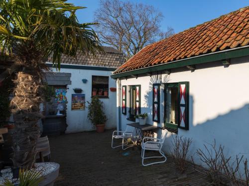 een wit huis met een palmboom en een tafel en stoelen bij Authentiek vakantiehuisje in Terneuzen