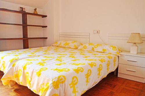 a bedroom with a bed with a yellow and white comforter at Apartamento El Corro: con parking en pleno centro de Comillas in Comillas