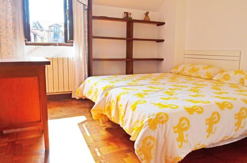 ein Schlafzimmer mit einem Bett mit einer gelben und weißen Decke in der Unterkunft Apartamento El Corro: con parking en pleno centro de Comillas in Comillas