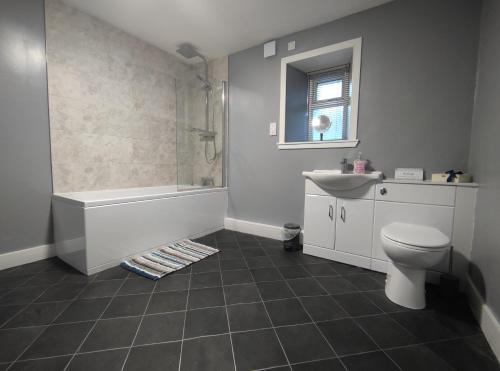 een badkamer met een bad, een toilet en een wastafel bij Dunvegan House in Helmsdale