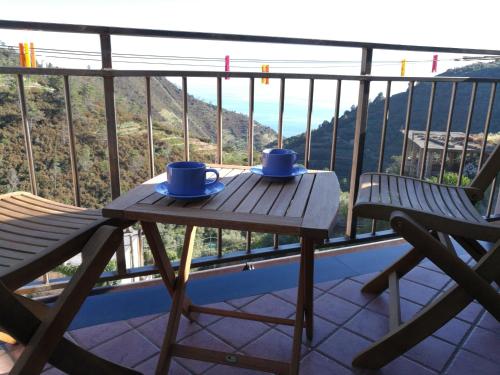 una mesa de madera con 2 tazas azules en el balcón en ☆ Terrace & Relax ☆ CASA FRANCESCHIN_ HOMY 5 TERRE, en Riomaggiore