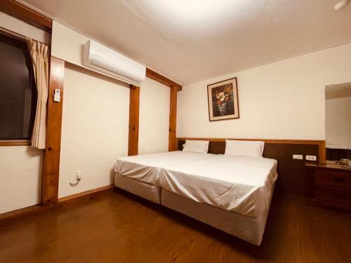 a bedroom with a white bed and a television at Taitung Garden Cabin in Taitung City