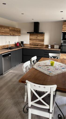 a kitchen with a wooden table and white chairs at Gîte Les Plains Champs in Labaroche